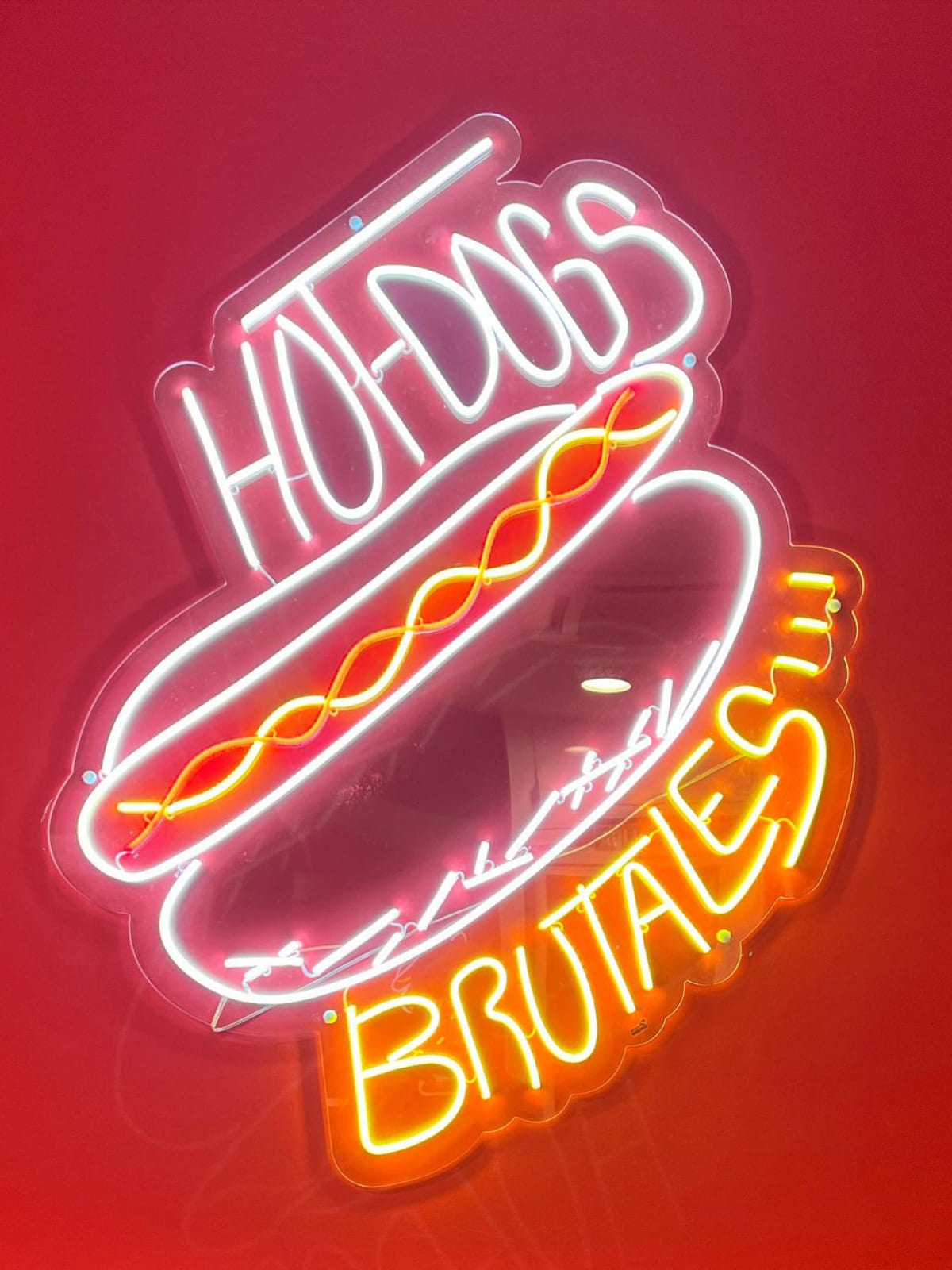 Luminoso cartel de neón con la frase 'HOT DOGS BRUTALES' en Dogo's Grill, destacando los mejores perritos calientes de Madrid