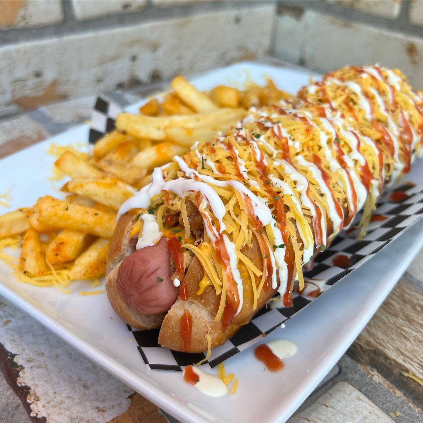 Perrito caliente deluxe de Dogo's Grill en Madrid, generosamente cubierto con queso, salsa y acompañado de patatas crujientes